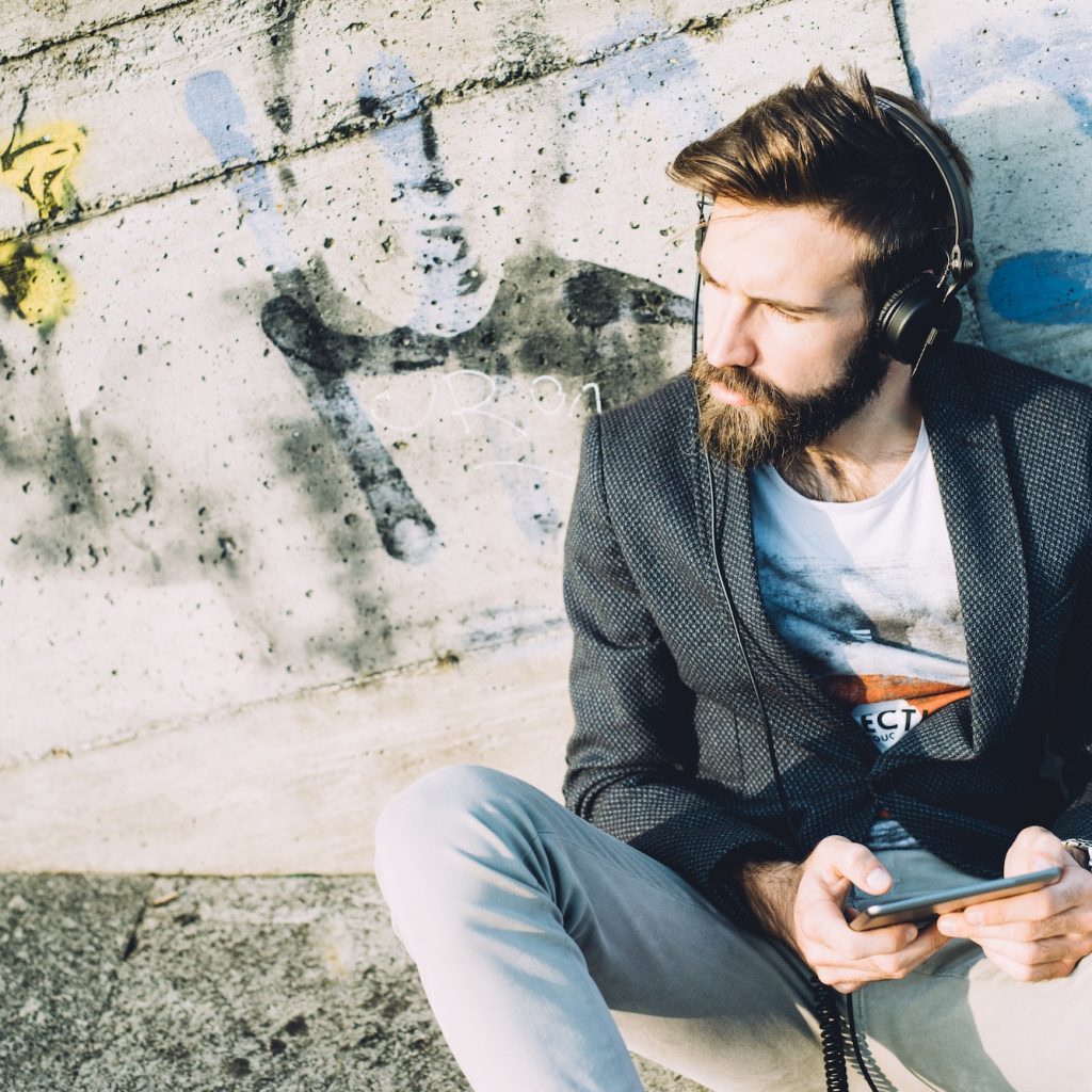 Young bearded man using tablet listening music